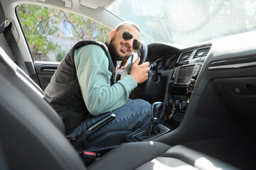Handsome young man hugging steering wheel in car. I love my car concept
