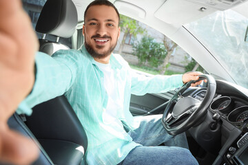 Handsome young man taking selfie in car. I love my car concept