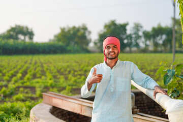 young indian farmer standing at agricultural field