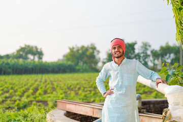 young indian farmer standing at agricultural field
