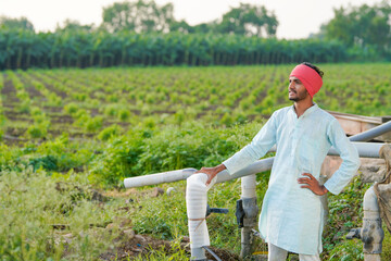 young indian farmer standing at agricultural field