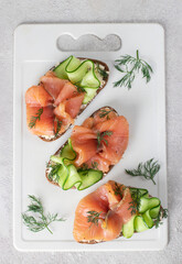 Sandwiches with salted salmon, cream cheese and cucumber on white board