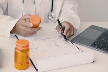 A female doctor reviews test results and diagnoses disease, records, prescribes medicine, and...