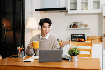 E learning online working concept. Man working on laptop computer, searching and taking note on paper notebook working sitting in the kitchen.