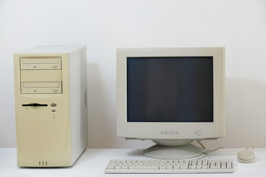 A classic desktop computer system from the past, featuring an old-fashioned CRT monitor, a beige tower unit, a keyboard, and a simple mouse, all isolated on a clean white surface.