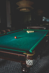 Cozy billiard room featuring classic green-felt pool tables; red and white balls arranged for play...