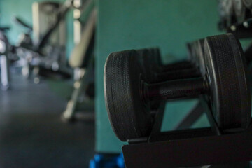 Fifteen-kilogram dumbbell rests on a rack in a modern hotel gym; shallow depth of field blurs the...