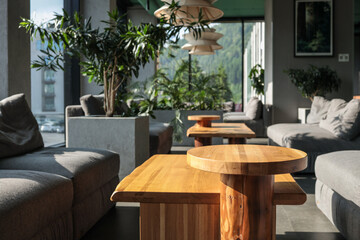 Bright hotel lounge with oak coffee tables, grey modular sofas, lush potted plants and sculptural...