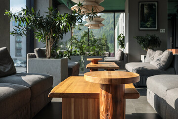 Bright hotel lounge with oak coffee tables, grey modular sofas, lush potted plants and sculptural...