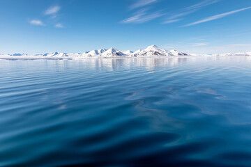The blue arctic ocean, pristine snow covered mountains and summer sky. Svalbard, a Norwegian...
