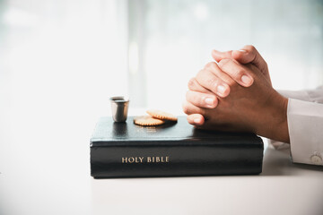 During the holy communion ceremony in church, a hand is extended in faith to receive the sacred...