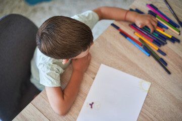 Young boy selecting markers while drawing at home