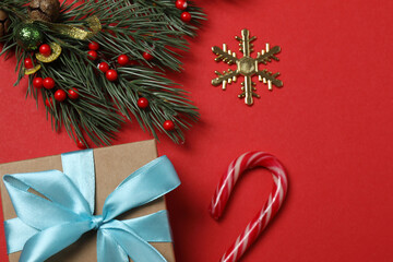 Top view of gift box trinket, fir branch, on red background, space for text