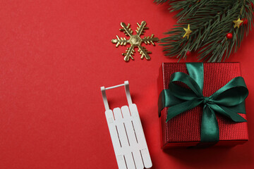 Top view of gift box trinket, fir branch, on red background, space for text