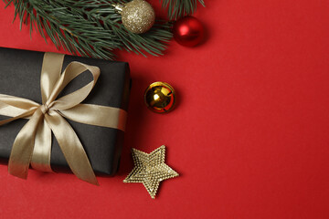 Top view of gift box trinket, fir branch, on red background, space for text