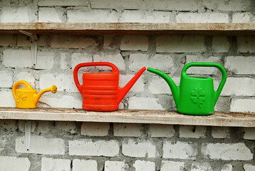 Watering cans on a brick shelf.