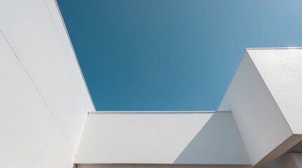 A Modern Building with White Facades and Sharp Angles Shot from Below Against a Clear Sky, Forming a Clean Geometry of Light and Form in Architectural Minimalism