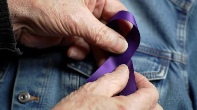 Hands folding a purple ribbon for awareness of cancer and epilepsy