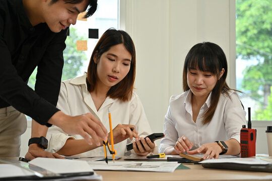 An Engineers and designers discussing blueprints and measurements at a modern office desk