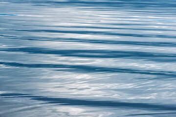 Rippling blue water surface reflecting light during midday at a tranquil lake