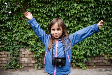 Young photographer raising arms with vintage camera and ivy wall background