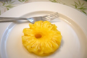 Pineapple ring on white plate with fork
