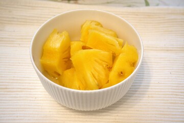 Chopped pineapple in white bowl.