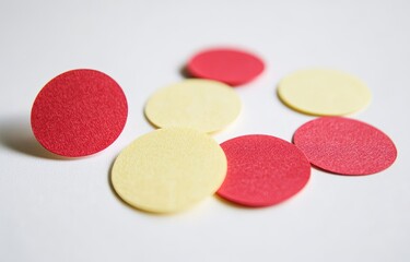 Red and yellow circular paper shapes scattered on white surface