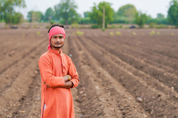 young indian farmer standing at agricultural field