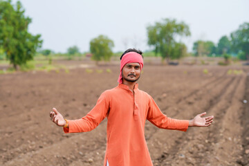 young indian farmer standing at agricultural field