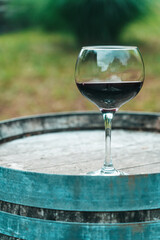 Glass of Red Wine on Old Oak Barrel in Rustic Cellar