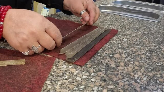 Closeup hands demonstrate how to make paper from papyrus plants