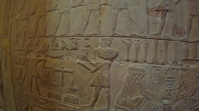 Hieroglyphics and Egyptian figures carved into sandstone tomb wall