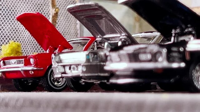 Miniature Mustang models on display with hoods open, captured from a low angle