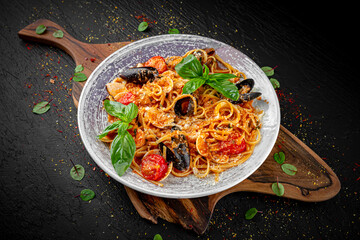 Italian pasta with shrimp, mussels, and calamari in a creamy sauce on a dark background. Classic seafood dish.