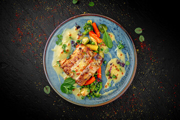 Baked salmon fillet served with a mix of vegetables on a dark background. Healthy gourmet dish.
