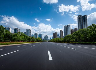 Obraz premium High-speed highway, an asphalt road with trees and buildings in the background. The wide-open plain is empty of cars on an early summer day. In the front view, white lines mark the right side for driv