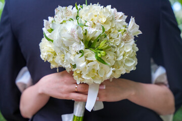 white bouquet, hands of the newlyweds. Close-up wedding couple bride