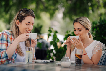 Two young women drinking coffee at outdoor cafe