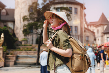 Caucasian female tourist with backpack exploring ba na hills in traditional Vietnamese hat