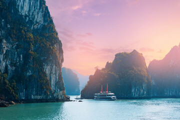 Scenic sunrise over Halong bay with with cruise boats and majestic cliffs and serene waters in...
