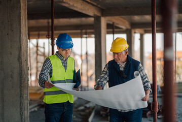 Architect and construction worker discussing blueprint on building site