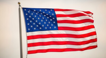 Fototapeta premium Full American Flag Waving on a Pole Against a Light Sky