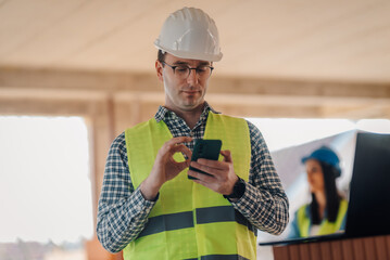 Construction engineer using smartphone inside building under construction