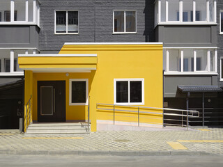 Beautiful modern colored entrance to a residential building and a ramp for wheelchair users.
