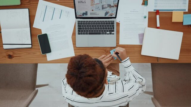 Documents, laptop and businesswoman in office for writing with report reminder on investment proposal. Paperwork, sticky note and financial manager tasks for corporate budget in workplace from above.