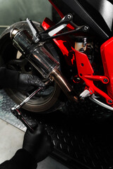Mechanic tightening bolts on motorcycle chrome exhaust system for peak performance. Custom exhaust...