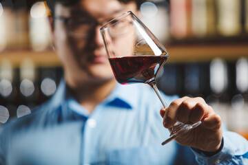 Close-Up View of Connoisseur Evaluating Red Wine in Stem Glass at Tasting Event
