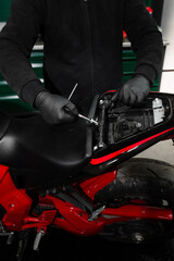 Technician carefully removes the motorcycle seat using tools to access internal components for...