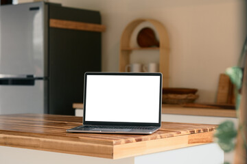 Laptop on a clean countertop with a refrigerator and kitchen decor in the background
